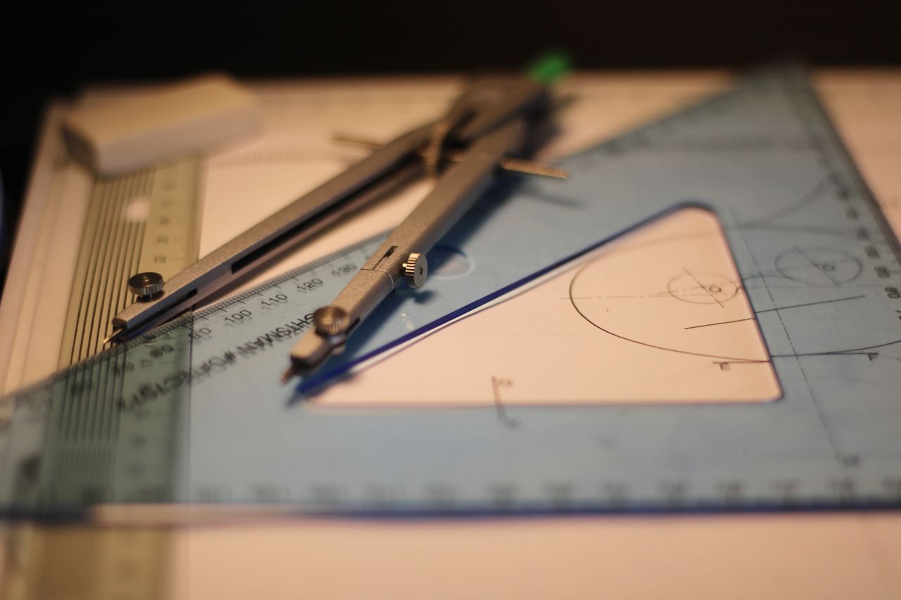 Precision drafting tools including compass and set square on a sketchpad.